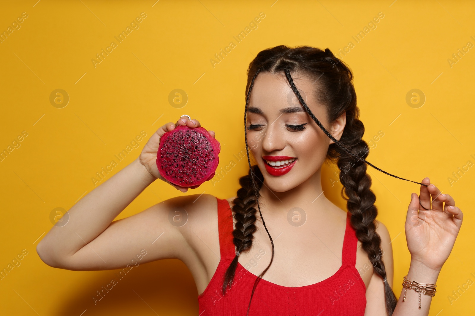 Photo of Young woman with fresh pitahaya on yellow background. Exotic fruit