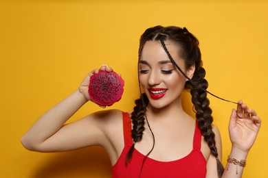 Photo of Young woman with fresh pitahaya on yellow background. Exotic fruit
