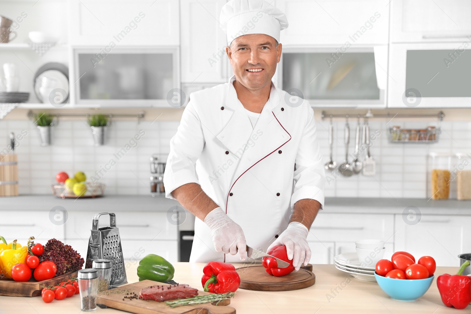 Photo of Professional chef cutting pepper on table in kitchen