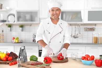 Professional chef cutting pepper on table in kitchen