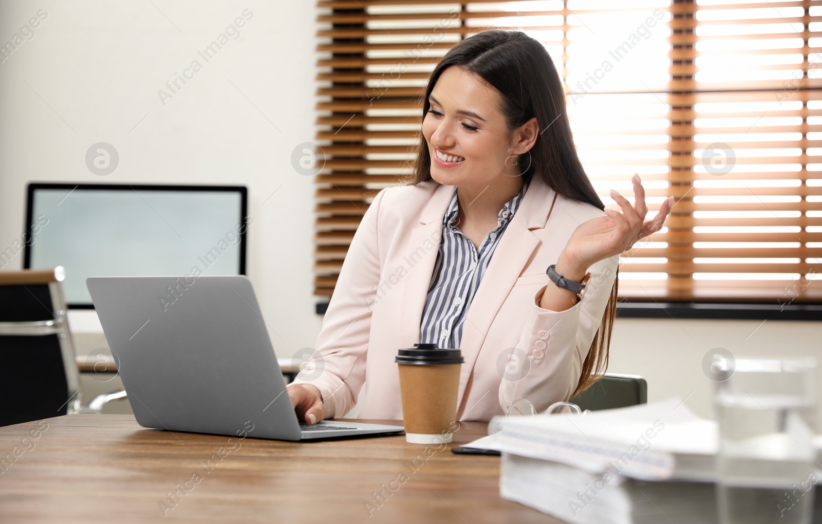 Photo of Young woman using video chat on laptop in home office