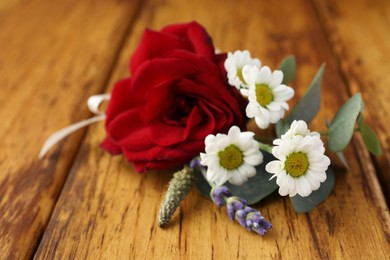 Small stylish boutonniere on wooden table, closeup