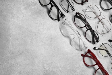 Photo of Many different glasses on light grey background, flat lay. Space for text