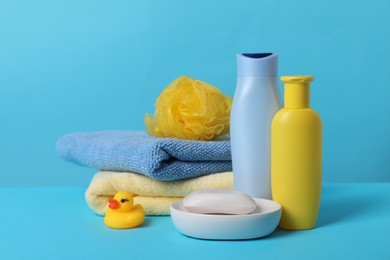 Baby cosmetic products, bath duck, sponge and towels on light blue background