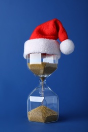 Hourglass and Santa hat on blue background. Christmas countdown