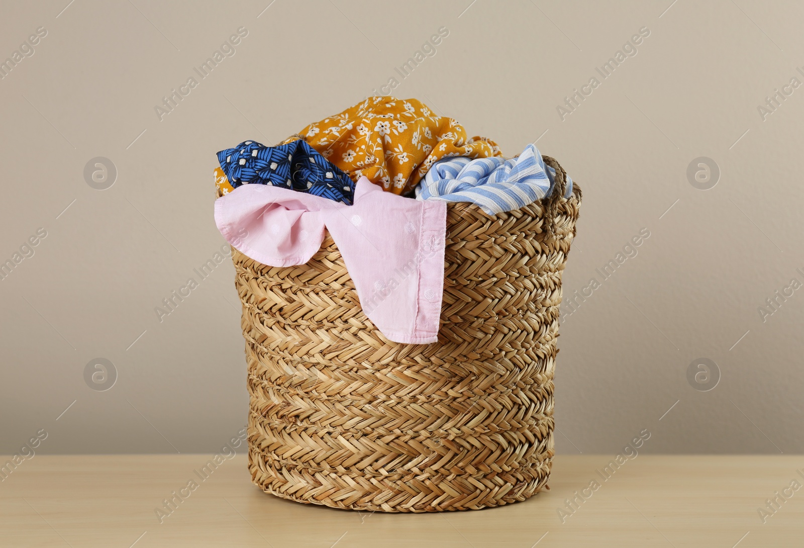 Photo of Wicker laundry basket with different clothes on wooden table