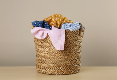 Wicker laundry basket with different clothes on wooden table