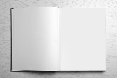 Photo of Open book on light grey table, top view. Space for text