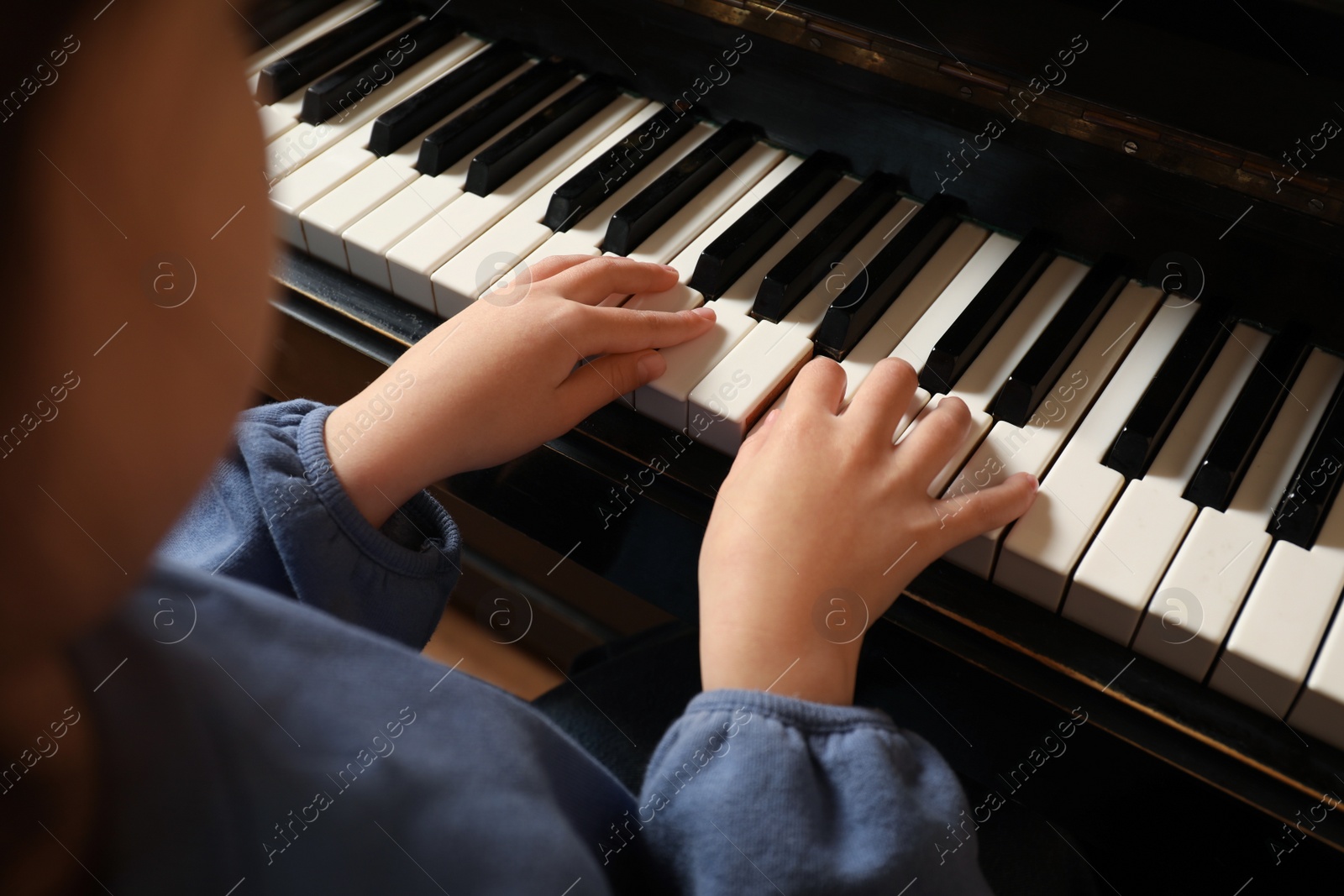 Photo of Little child playing piano, closeup. Music lesson