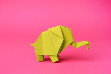 Photo of Yellow paper elephant on pink background. Origami art