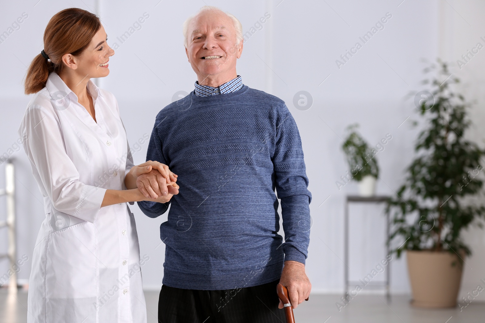 Photo of Elderly man with female caregiver indoors. Space for text