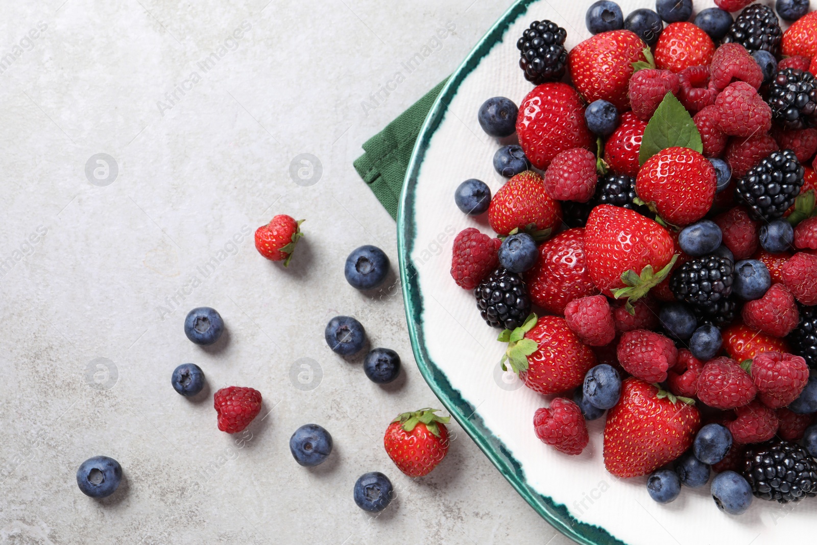 Photo of Different fresh ripe berries on light grey table, flat lay