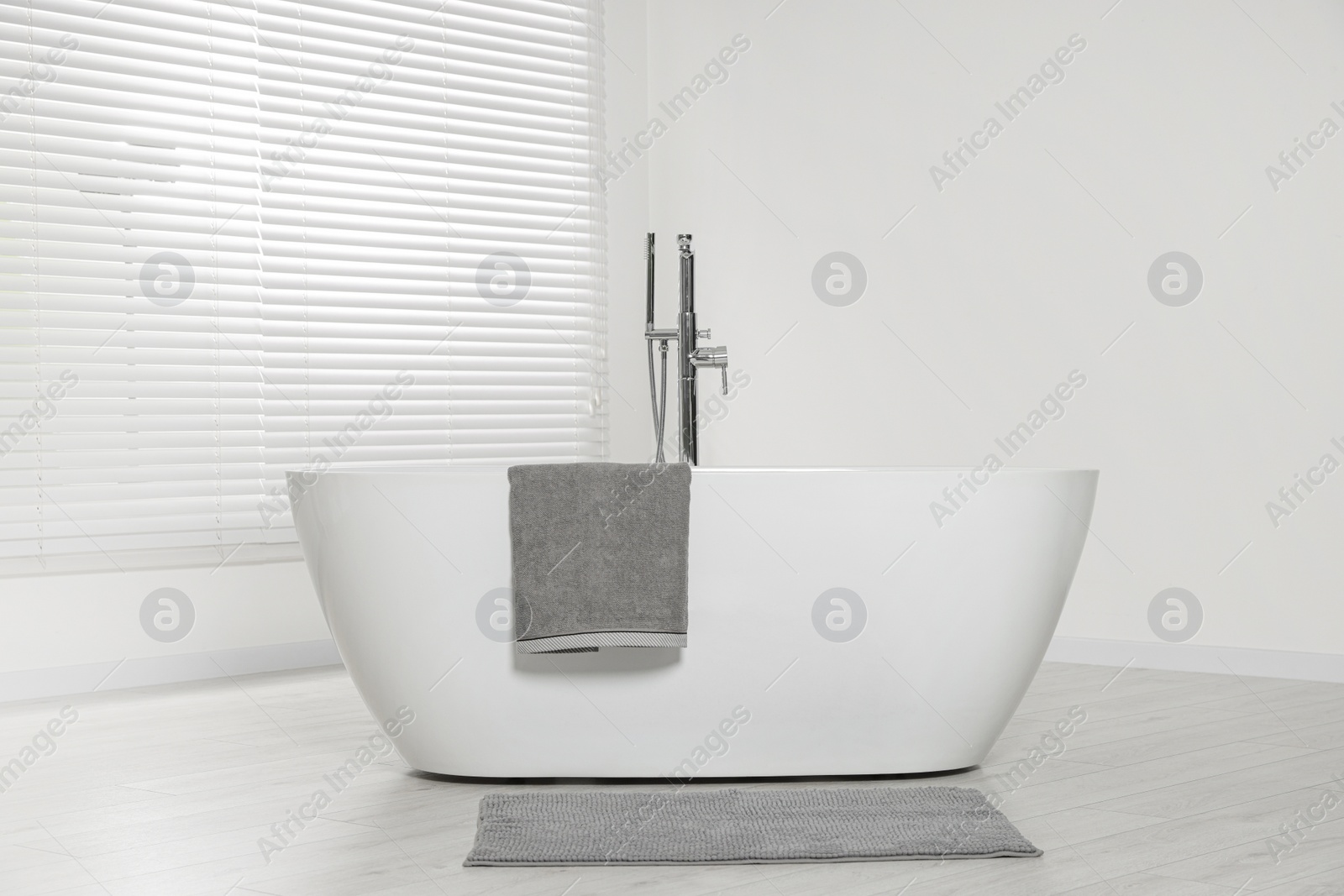 Photo of Stylish bathroom interior with ceramic tub and terry towel