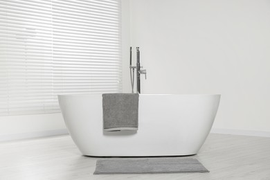 Stylish bathroom interior with ceramic tub and terry towel