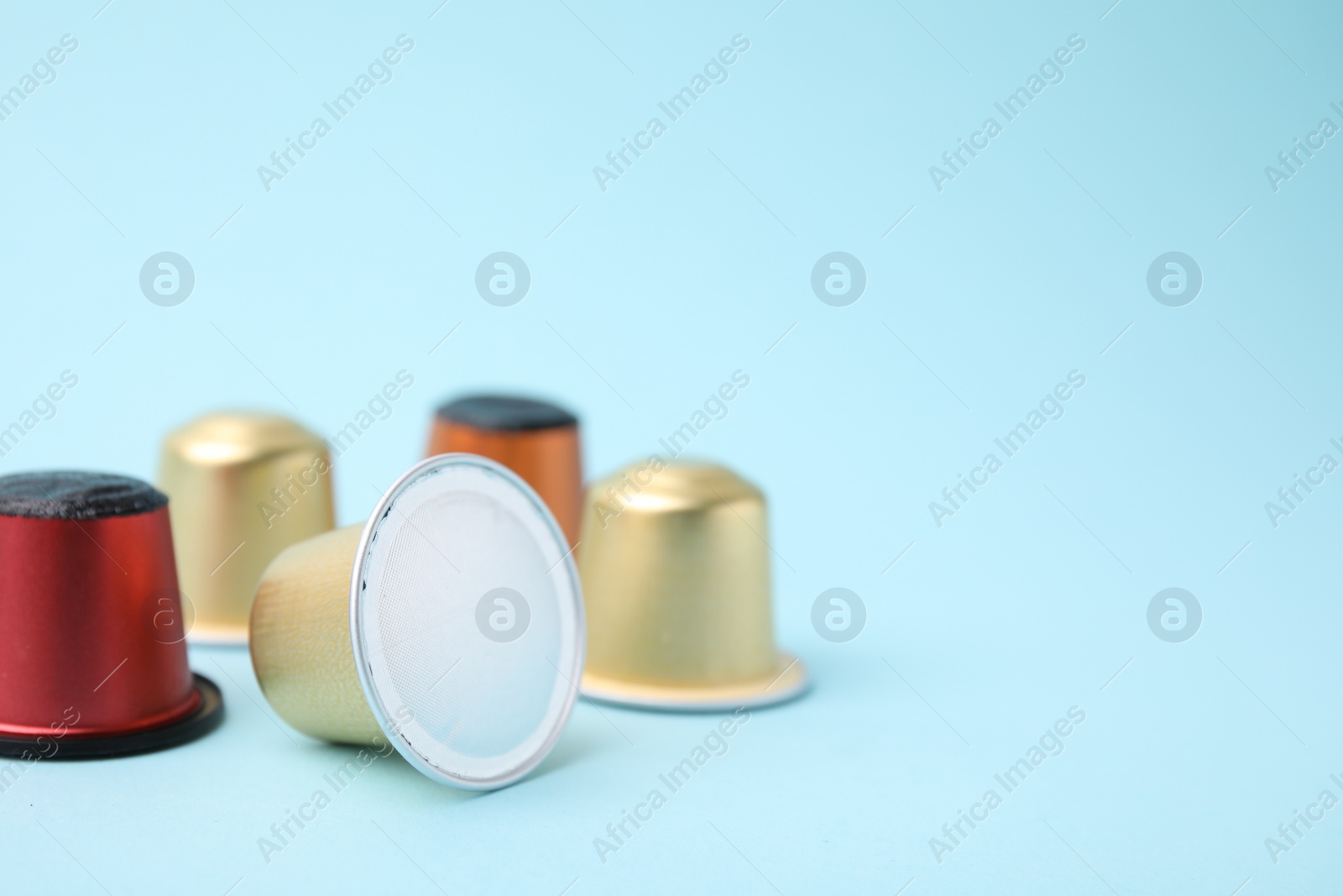 Photo of Many coffee capsules on light blue background, closeup. Space for text
