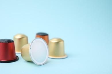 Many coffee capsules on light blue background, closeup. Space for text