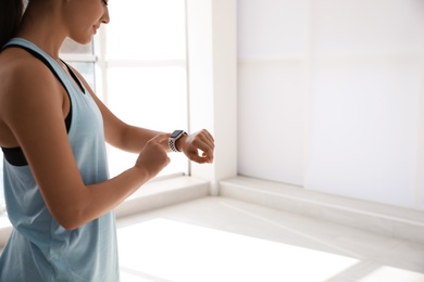 Photo of Woman checking fitness tracker in gym, closeup. Space for text