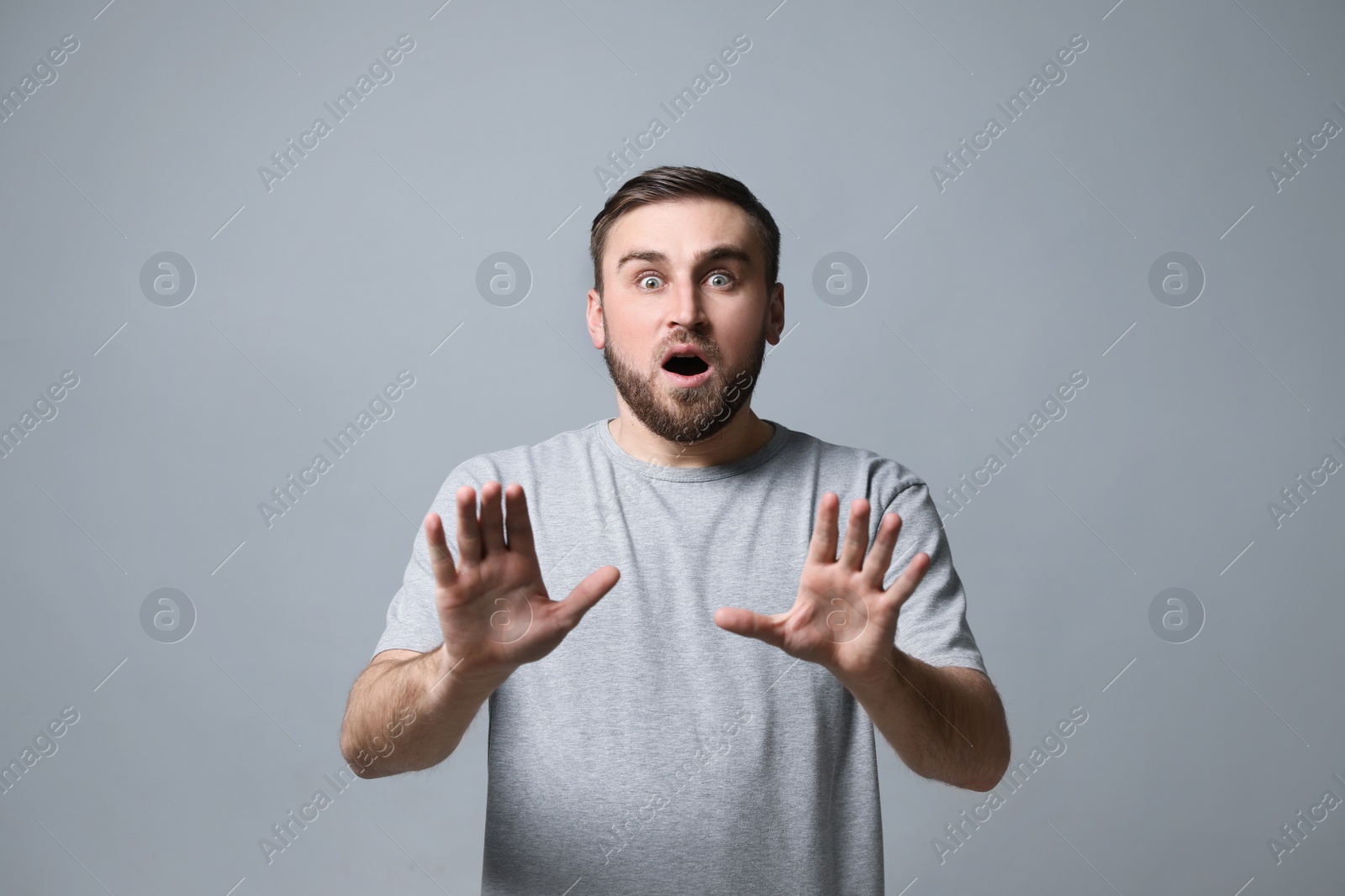 Photo of Young man feeling fear on grey background