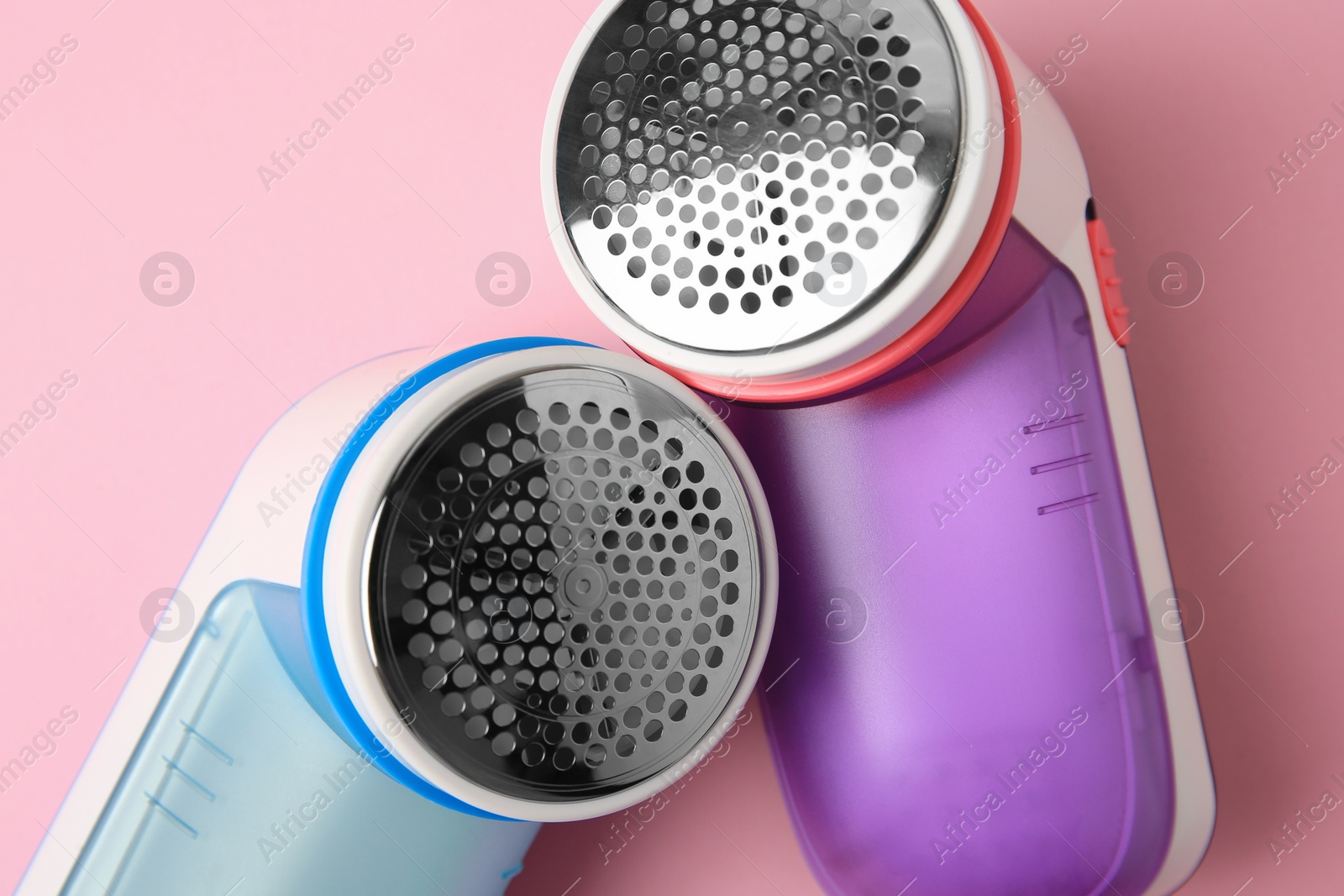 Photo of Modern fabric shavers on pink background, flat lay