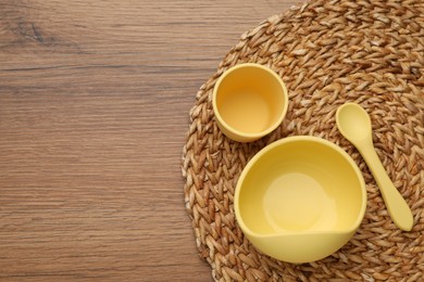 Photo of Set of plastic dishware on wooden background, top view with space for text. Serving baby food