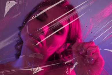 Photo of Fashionable portrait in neon lights. Beautiful young woman posing through transparent film