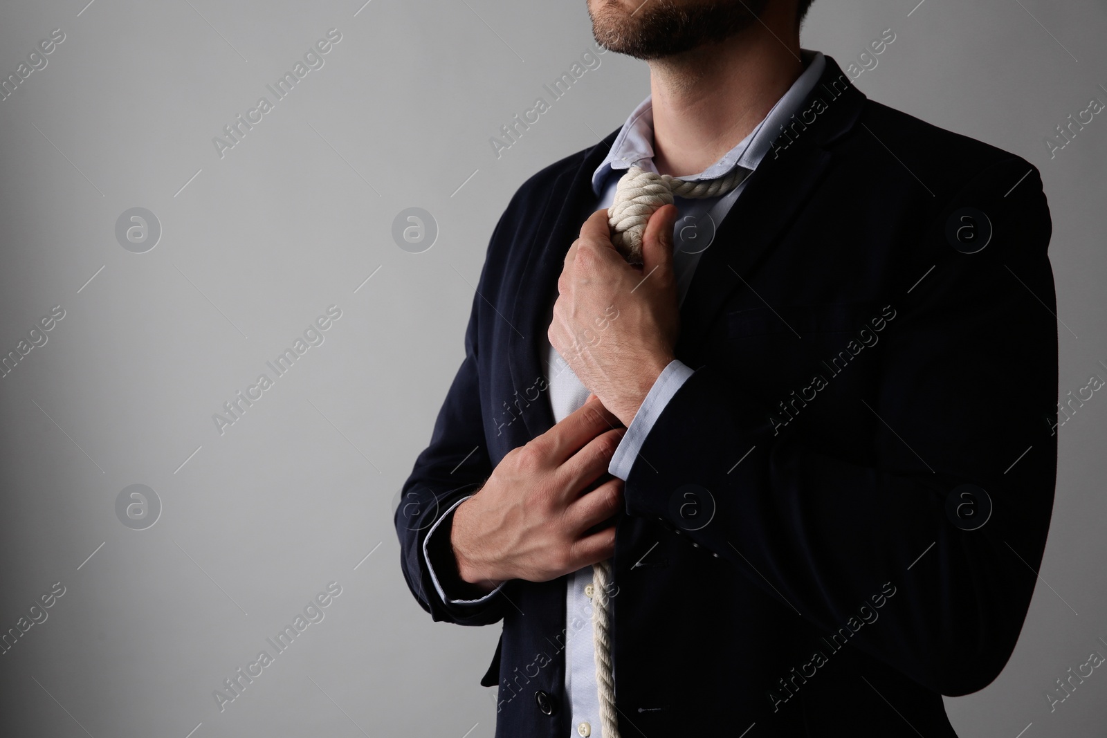 Photo of Businessman with rope noose on neck against light grey background, closeup. Space for text