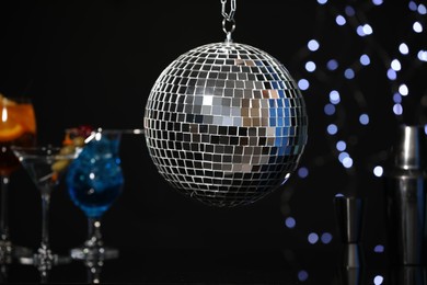 Photo of Shiny disco ball hanging over bar counter with cocktails in nightclub