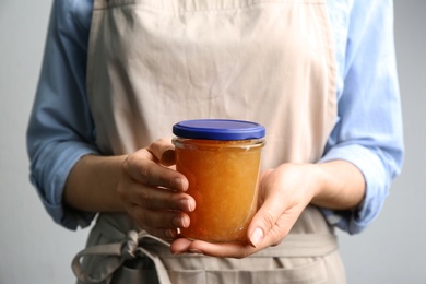 Photo of Woman with jar of delicious pear jam, closeup