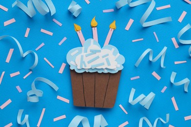 Photo of Birthday party. Paper cupcake and confetti on light blue background, flat lay