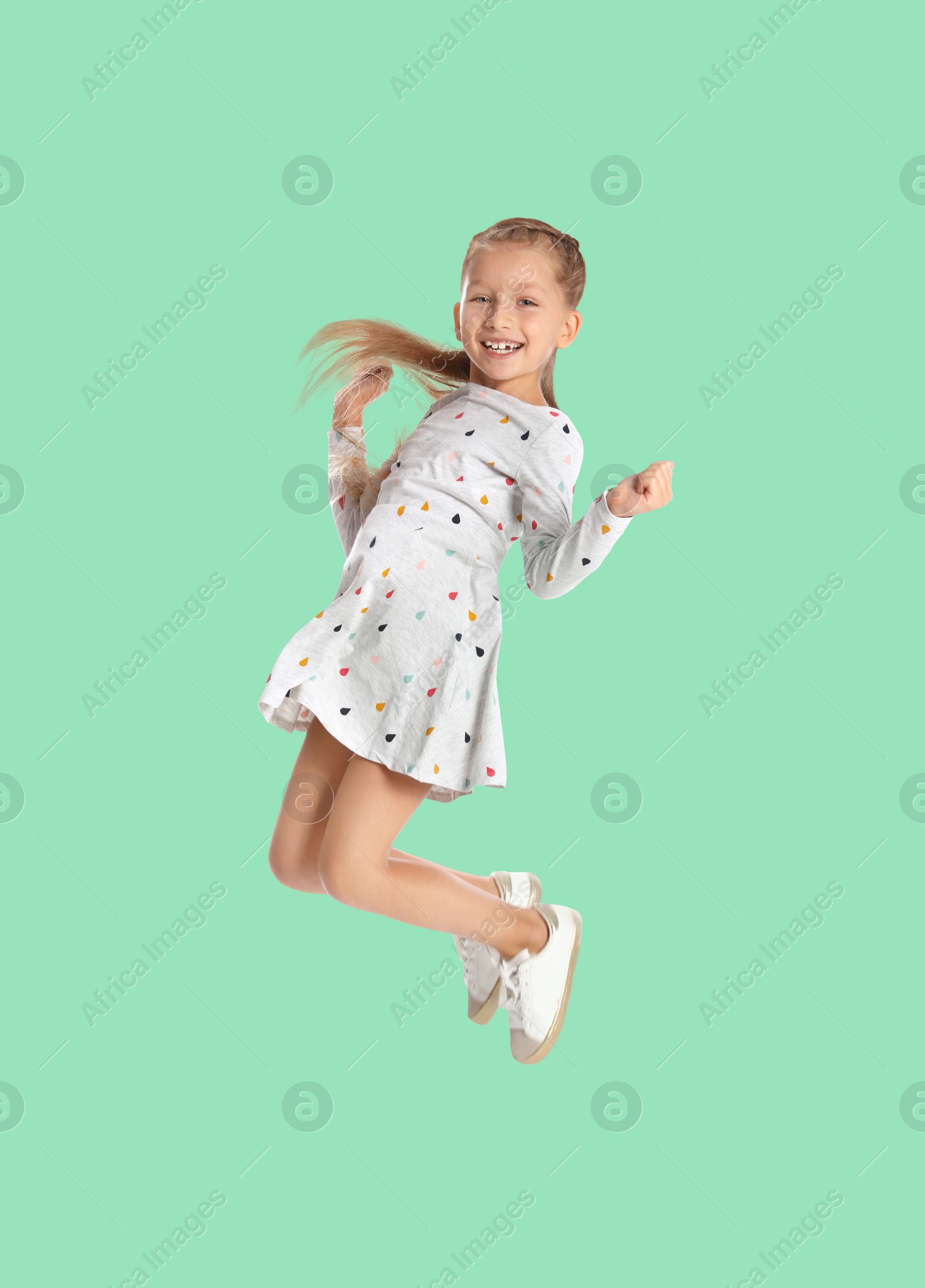 Image of Happy cute girl jumping on aquamarine background