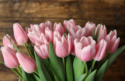 Photo of Beautiful pink spring tulips on wooden background, closeup