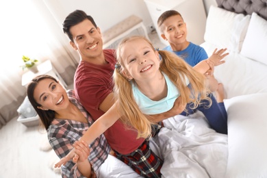 Photo of Happy young family with children having fun in bedroom