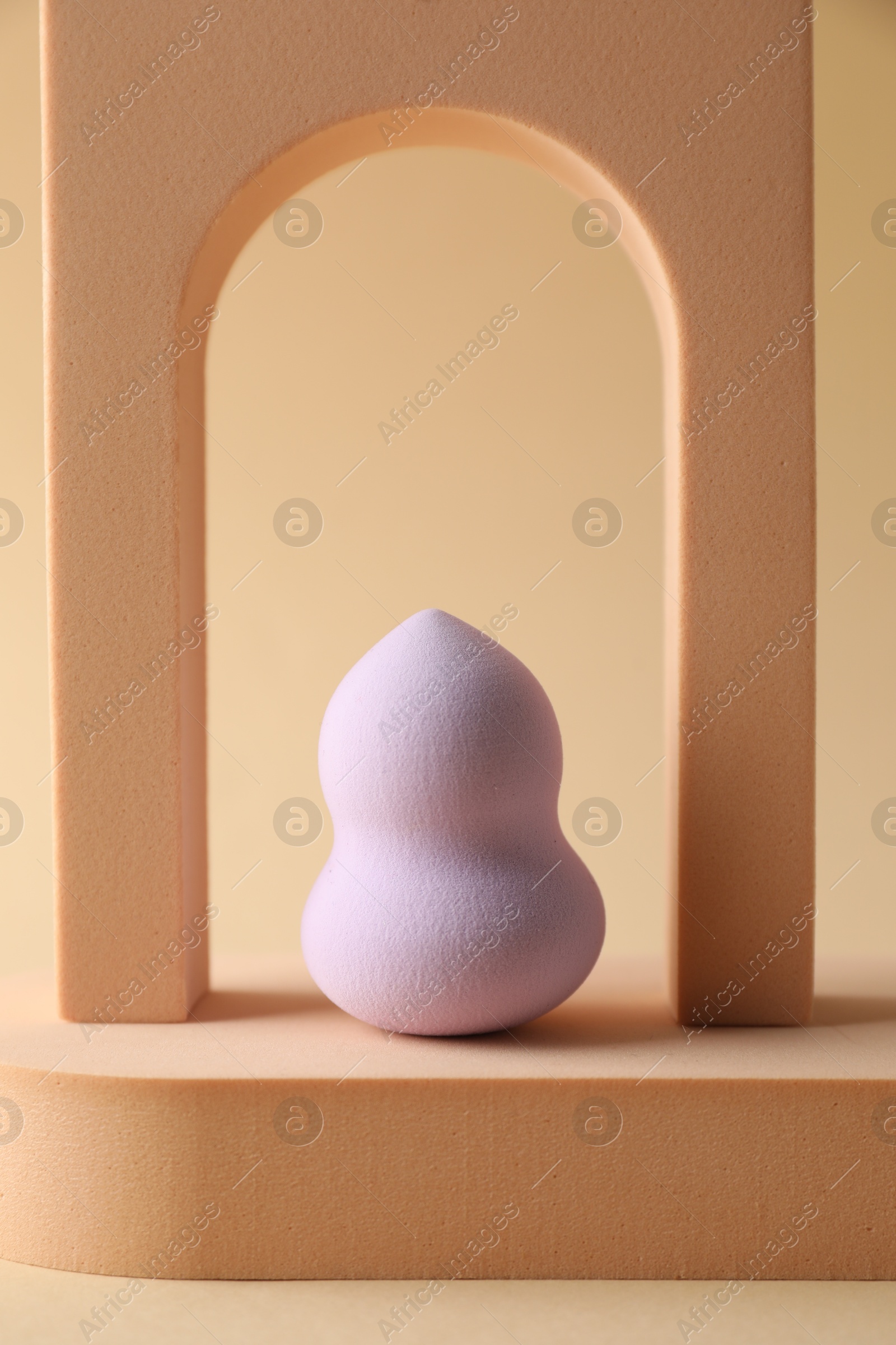 Photo of Stylish presentation of makeup sponge on beige background