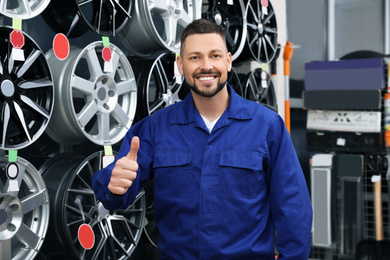 Male mechanic near alloy wheels in auto store