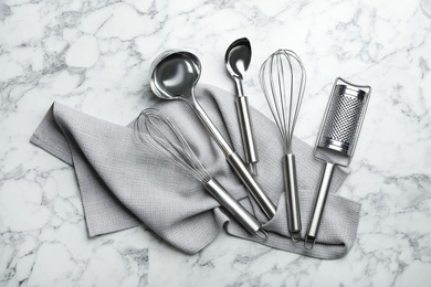 Photo of Set of clean kitchen utensils and napkin on marble background, top view