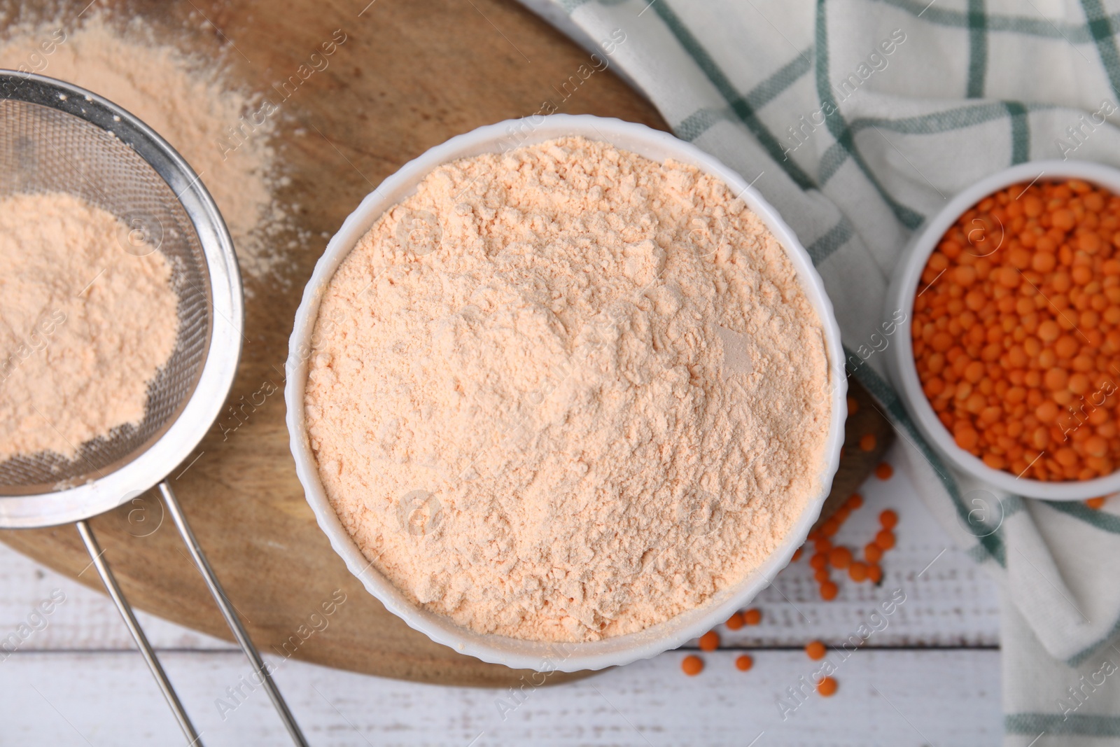 Photo of Bowl of lentil flour and seeds on white wooden table, flat lay