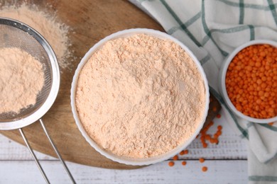 Photo of Bowl of lentil flour and seeds on white wooden table, flat lay