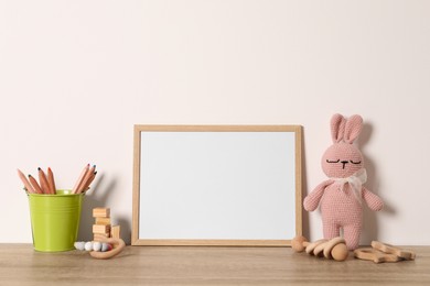 Empty square frame, stationery and different toys on wooden table