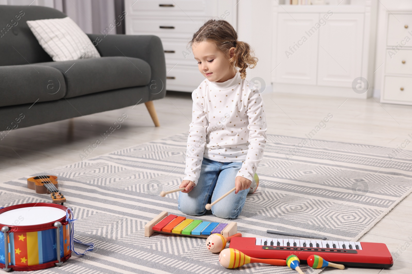 Photo of Little girl playing toy xylophone at home