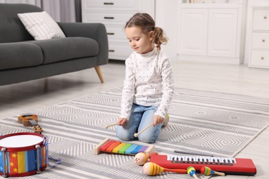 Photo of Little girl playing toy xylophone at home