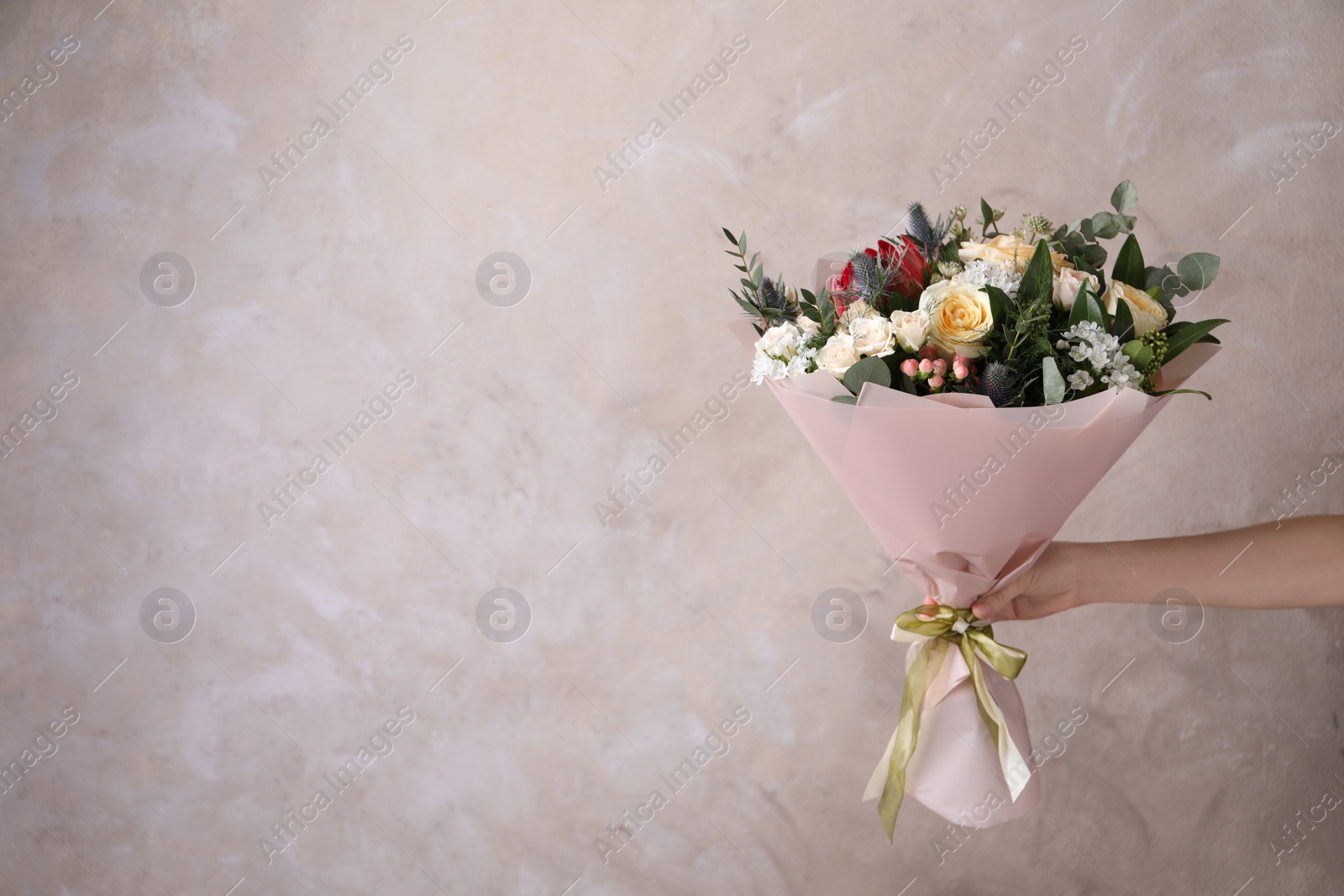 Photo of Woman with bouquet of beautiful roses on beige background, closeup. Space for text