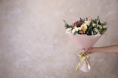 Photo of Woman with bouquet of beautiful roses on beige background, closeup. Space for text