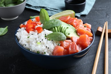 Photo of Delicious poke bowl with salmon, spinach and avocado served on black table