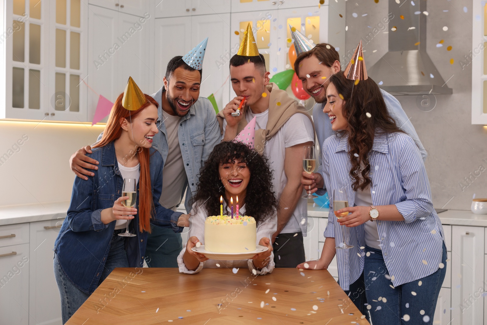 Photo of Happy friends with tasty cake celebrating birthday in kitchen