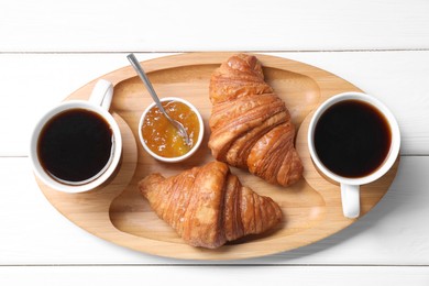 Photo of Tasty breakfast. Cups of coffee, jam and croissants on white wooden table, top view