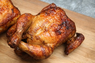 Photo of Delicious grilled whole chickens on wooden board, closeup