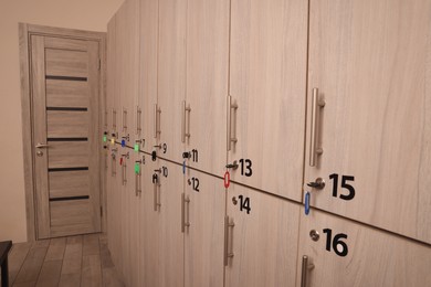Photo of Many numbered wooden lockers with keys indoors