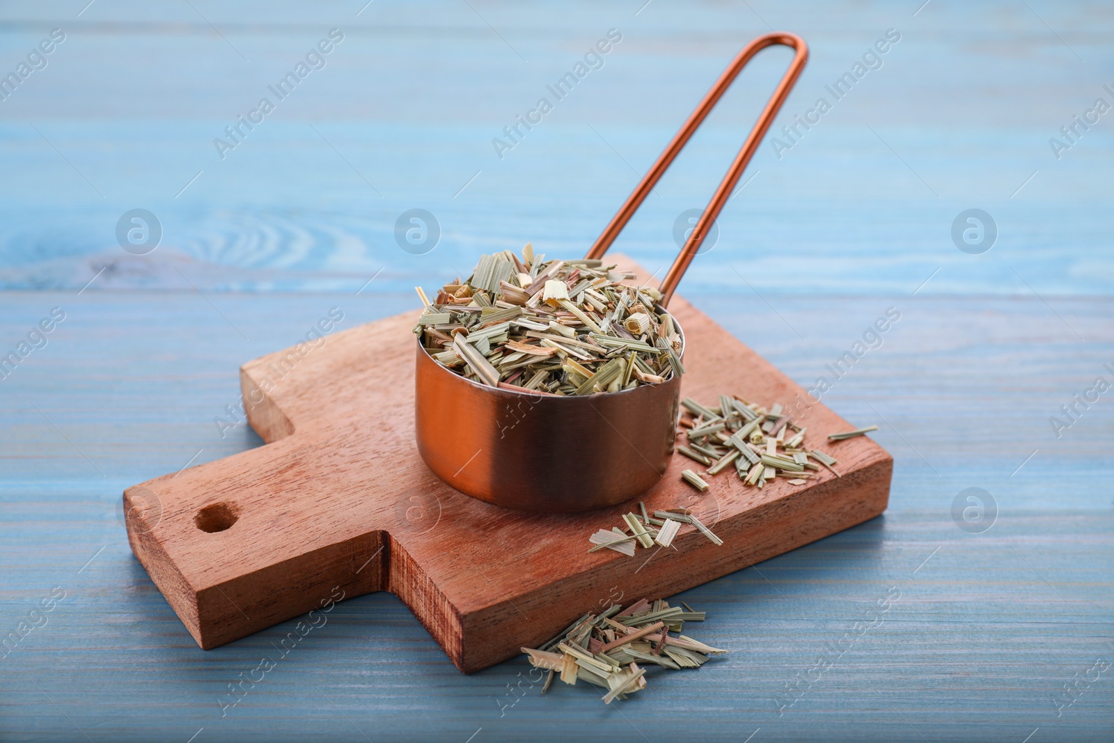 Photo of Small saucepan with aromatic dried lemongrass on light blue wooden table