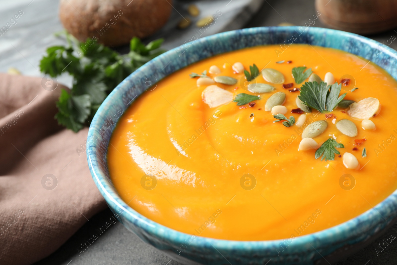 Photo of Delicious pumpkin soup in bowl on table, closeup