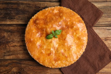 Delicious pie with meat and basil on wooden table, flat lay